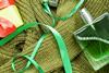 Styled image of a green bottle of perfume and green jumper with Christmas ribbons
