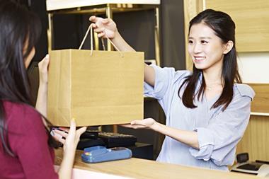 Shop assistant passing bag to customer